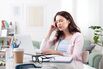 Young woman with a headache at home, using her laptop while sitting at a cozy desk. Representing remote work, studying, online learning, or social media use in a stressful lifestyle setting