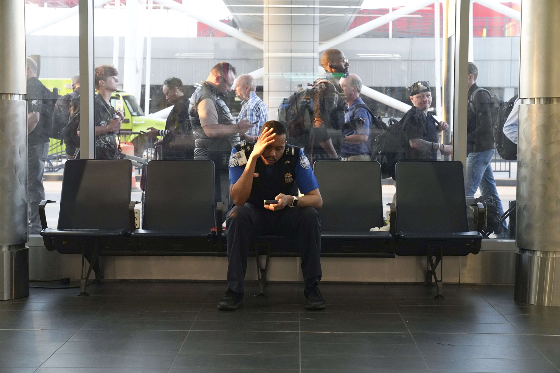 A TSA agent sits by a window as travelers stand in long lines at Atlanta Hartsfield-Jackson International Airport on March 23. Photographer: Megan Varner/Getty Images