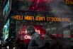 Monitors displaying market information are seen through a window reflecting pedestrians in Times Square in New York.