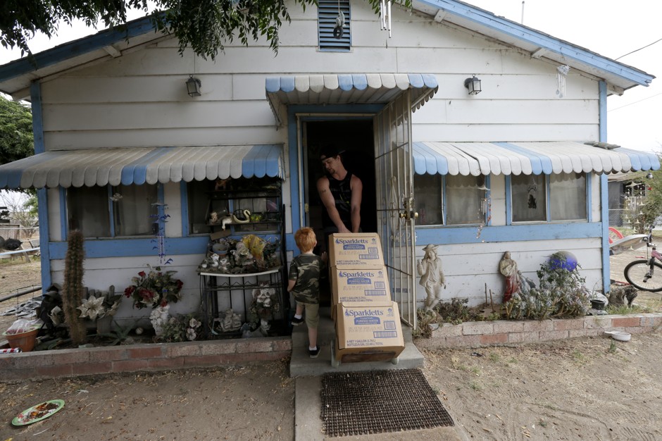 A man hauls boxes of bottled water into his home on the outskirts of Tulare, California.