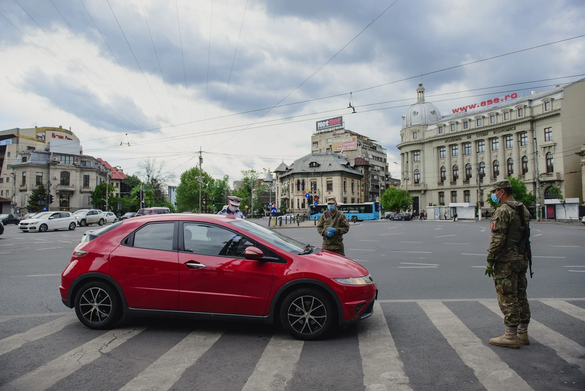 A police officer and soldiers halt a driver while enforcing lockdown measures at Piata Romana traffic intersection in Bucharest, Romania, on May 5.