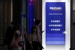 Signage for Mizuho Financial Group Inc. displayed outside a Mizuho Bank Ltd., Mizuho Trust & Banking Co. and Mizuho Securities Co. branch at night in Tokyo, Japan, on Monday, April 25, 2022. 