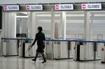 An employee walks past closed departure gates in a departure hall at Narita Airport in Narita, Chiba Prefecture, Japan, on Tuesday, Nov. 30, 2021. 