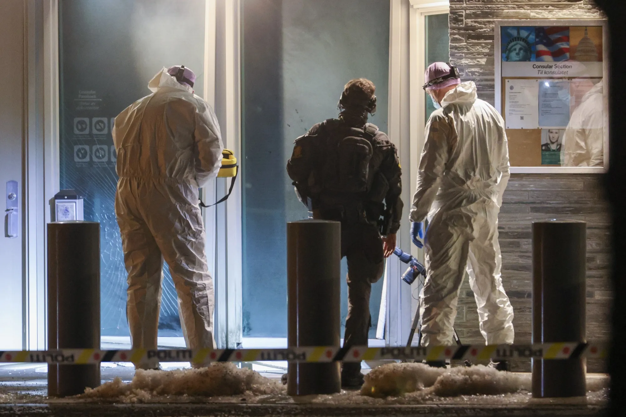 Forensic experts and a police officer stand in front the entrance of the US embassy after a loud bang was reported during the night in Oslo on March 8.&nbsp;