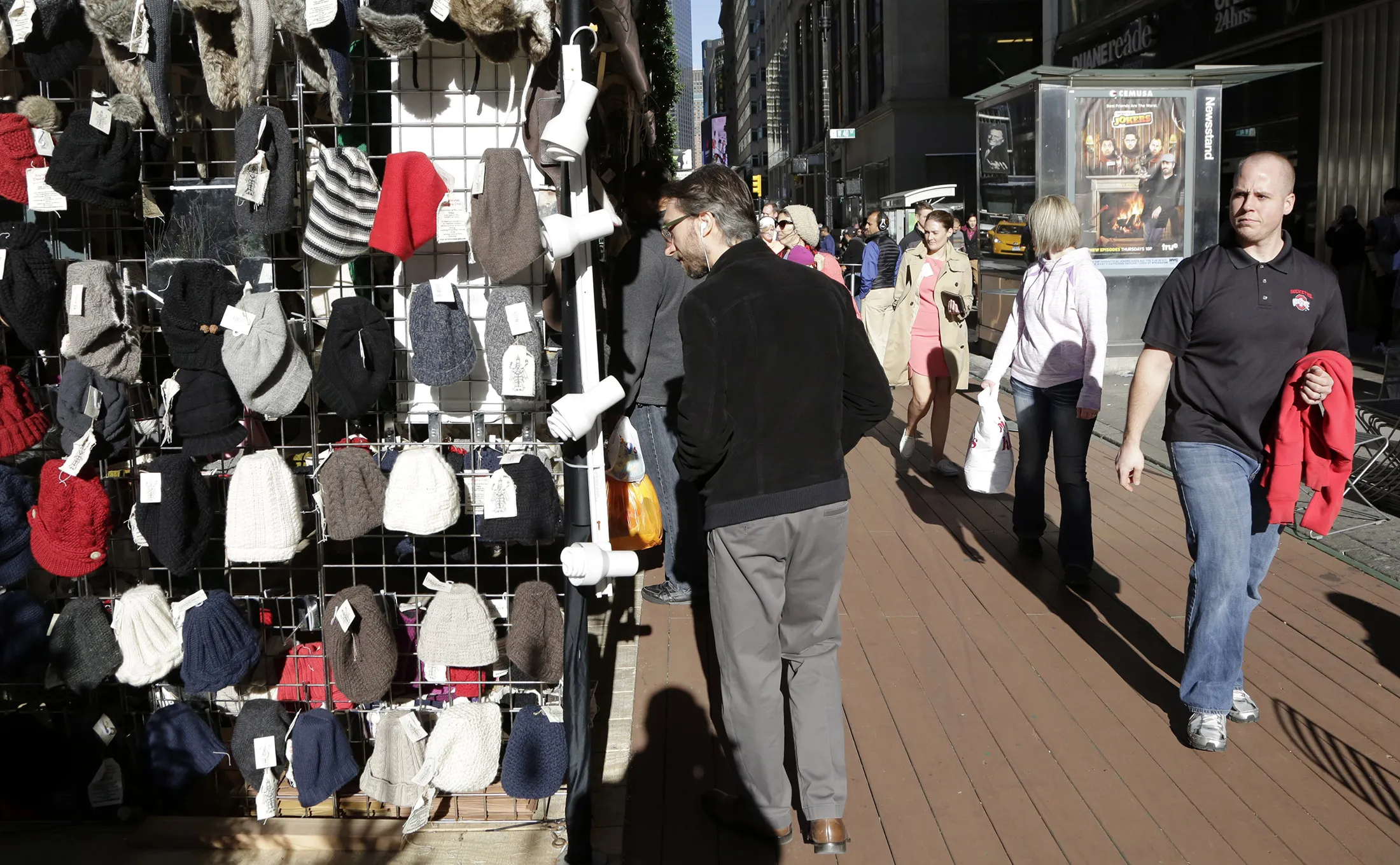 Pedestrians walk on the sidewalk past winter hats for sale in New York, on Dec. 15.
