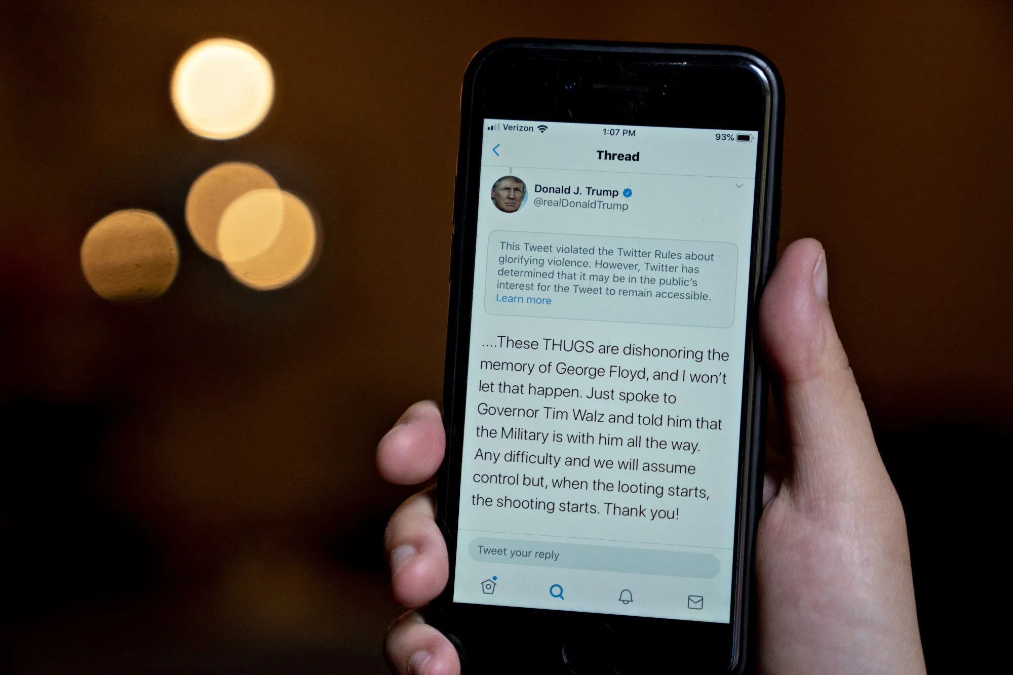 A tweet by U.S. President Donald Trump with a rule-violation notice that includes the phrase "when the looting starts, the shooting starts" is displayed on a smartphone on May 29.