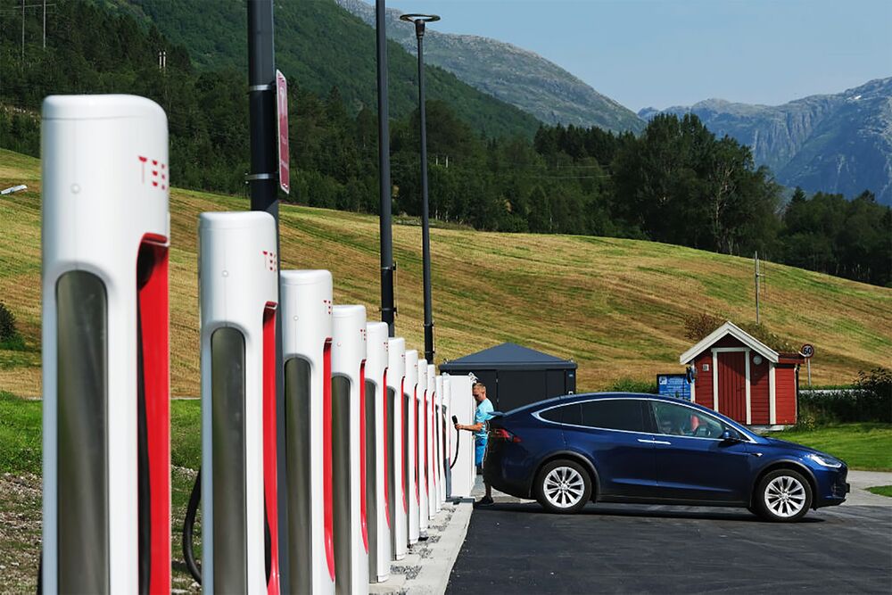 A driver prepares to charge his Tesla car at a Tesla Supercharger charging station in August 2020 in Skei, Norway. 