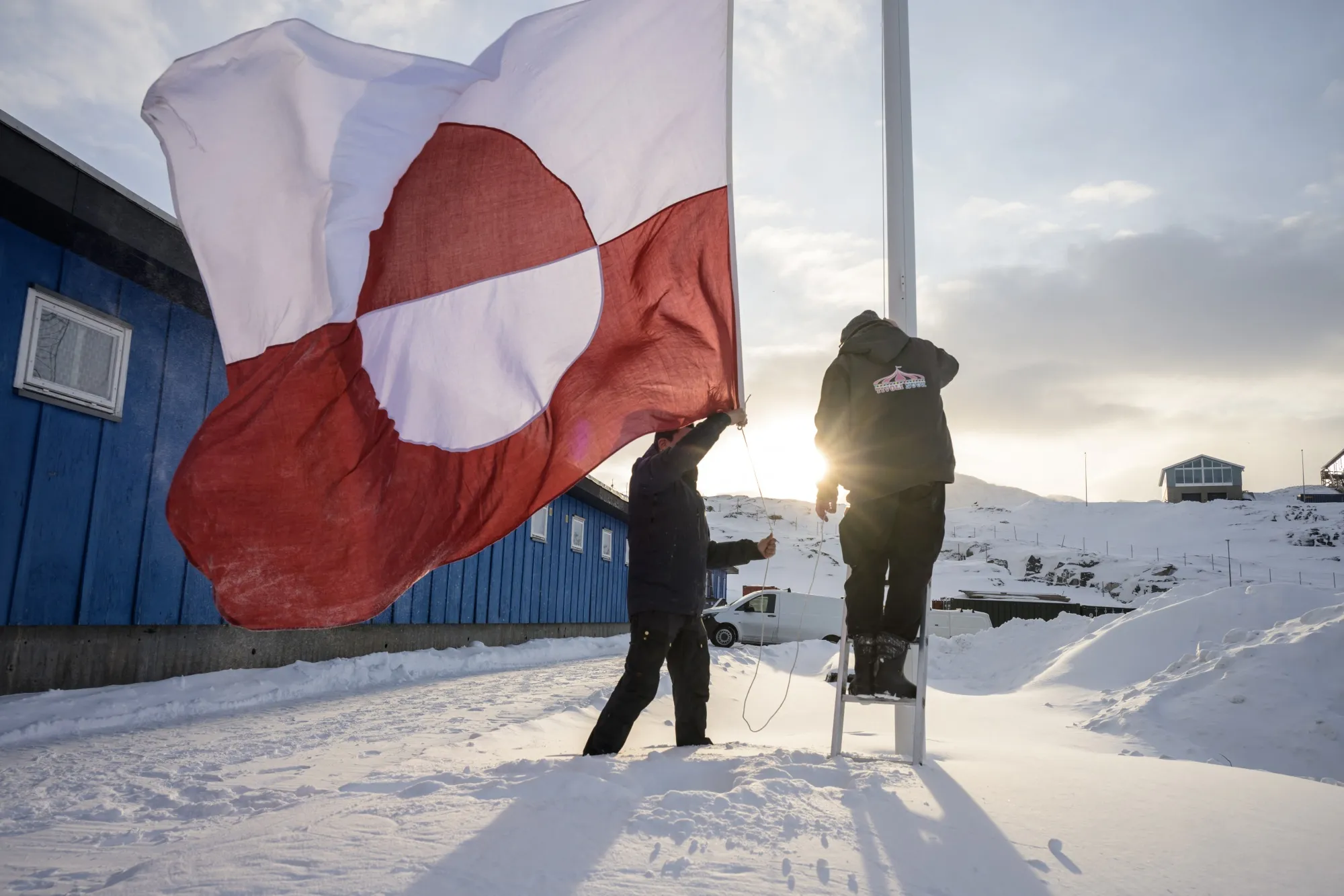 Men hoist a Greenlandic flag&nbsp;in Nuuk.