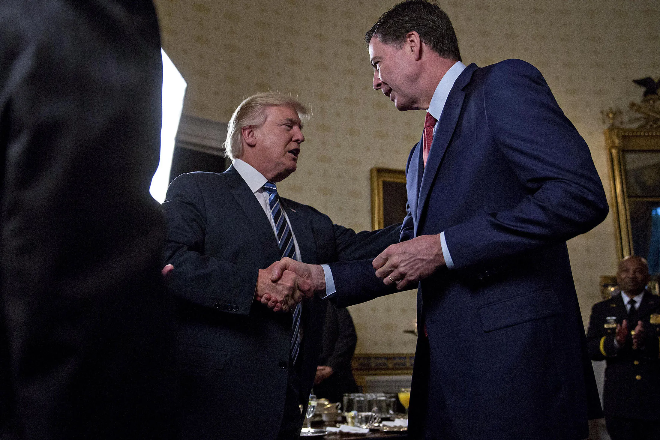 President Donald Trump shakes hands with James Comey, director of the Federal Bureau of Investigation (FBI), during an Inaugural Law Enforcement Officers and First Responders Reception in the Blue Room of the White House in Washington on Jan. 22, 2017.
