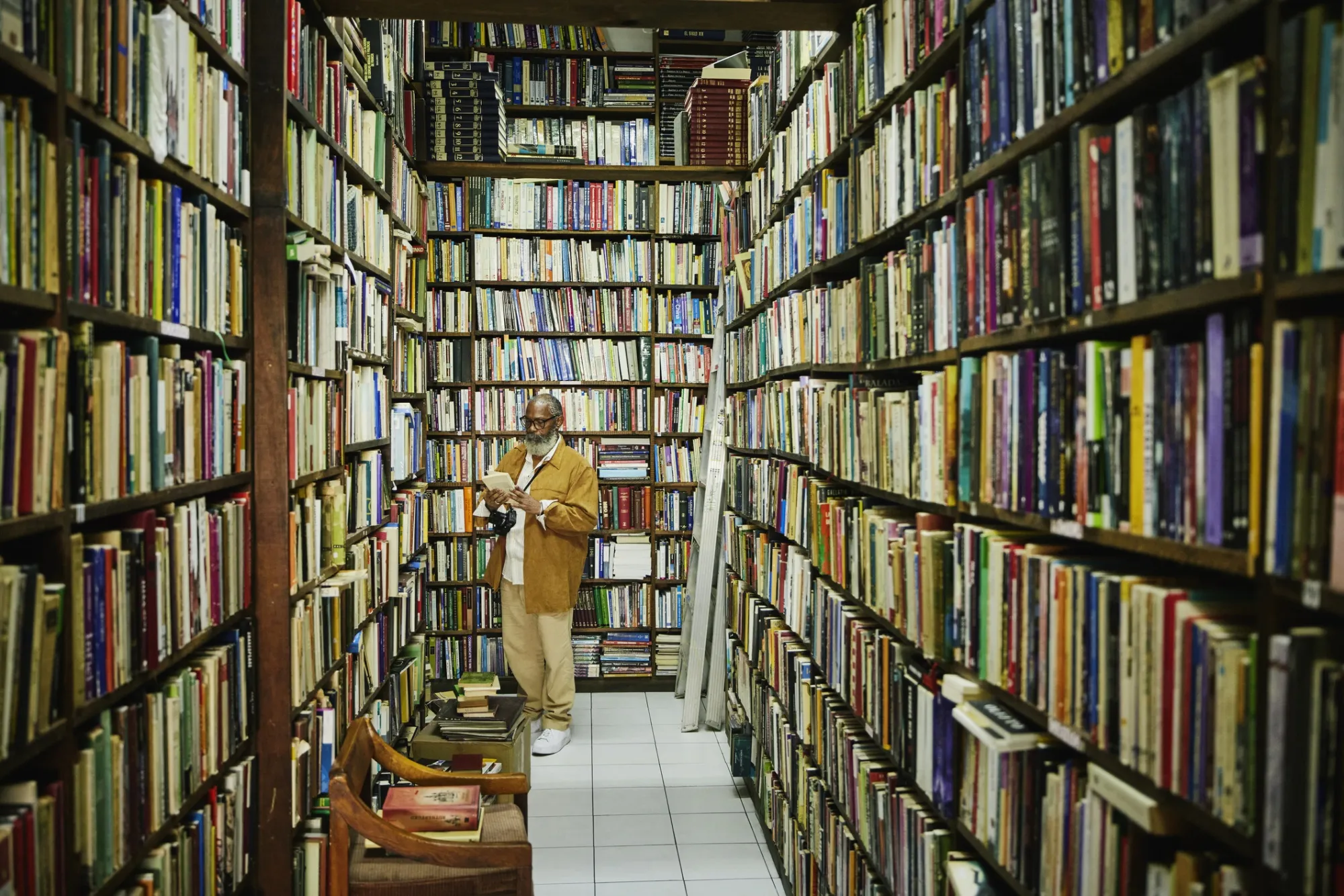 Wide shot senior man browsing in antique bookstore during city vacation