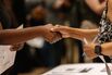 A recruiter shakes hands with an attendee at a career air in the US.
