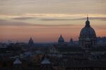 Church domes stand on the city skyline at dusk in Rome, Italy.