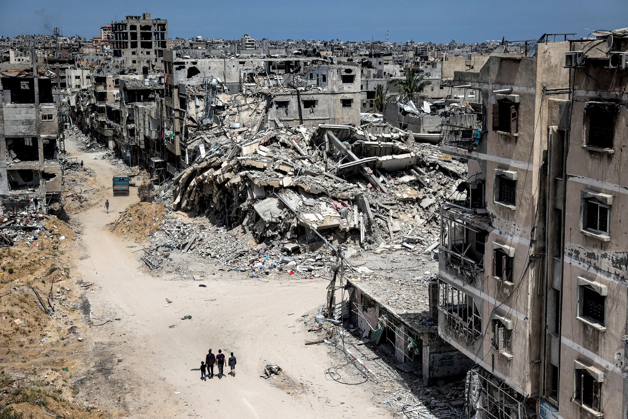 People walk past destroyed buildings in Khan Yunis on April 22.
