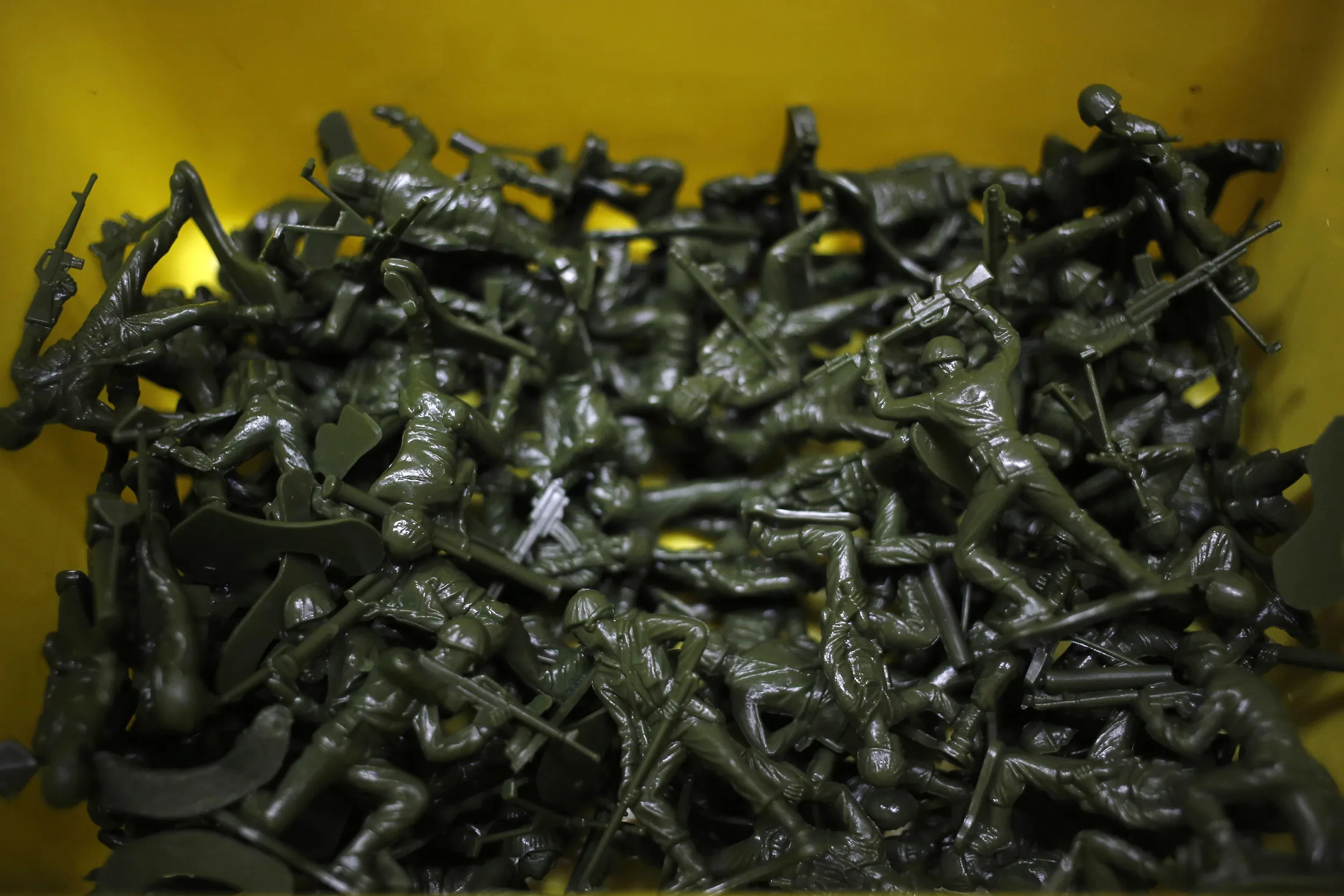 Green plastic army men are seen piled in a container after being manufactured by J.K. Manufacturing Co. in Kalkaska, Michigan U.S., on Wednesday, Dec. 7, 2016.

