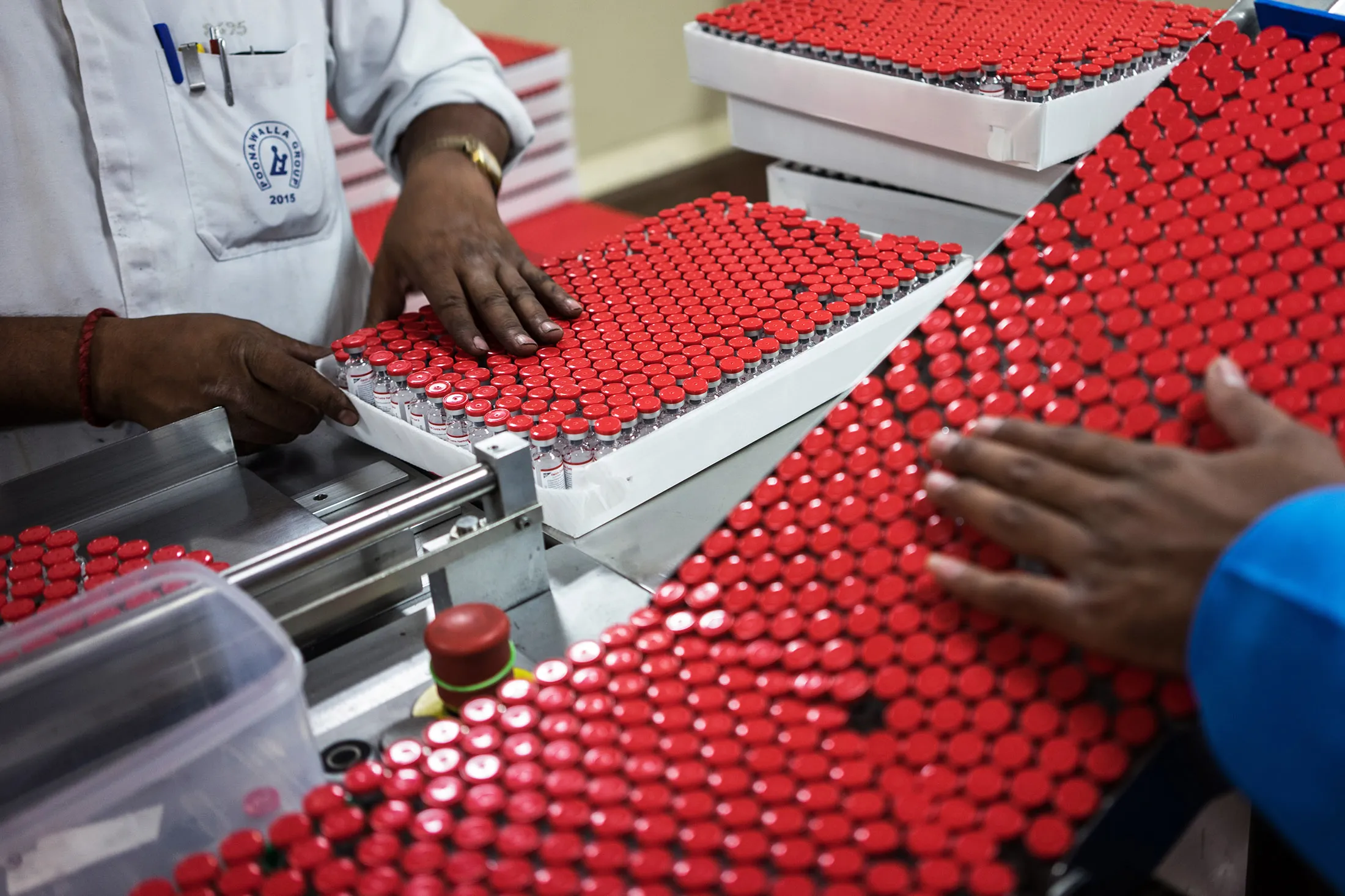 An employee, left, arranges labeled vaccine vials into a box as they exit a machine in the labeling unit at the Serum Institute of India Ltd. pharmaceutical plant in Pune, Maharashtra, India, on Monday, May 4, 2015. Serum, Asia's largest vaccine maker, will look at a possible merger with generic drugmaker Cipla Ltd. if the European venture between the two companies succeeds.
