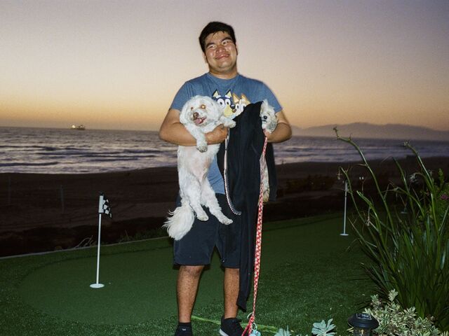 Man holding doodles on a putting green in Manhattan Beach, CA.