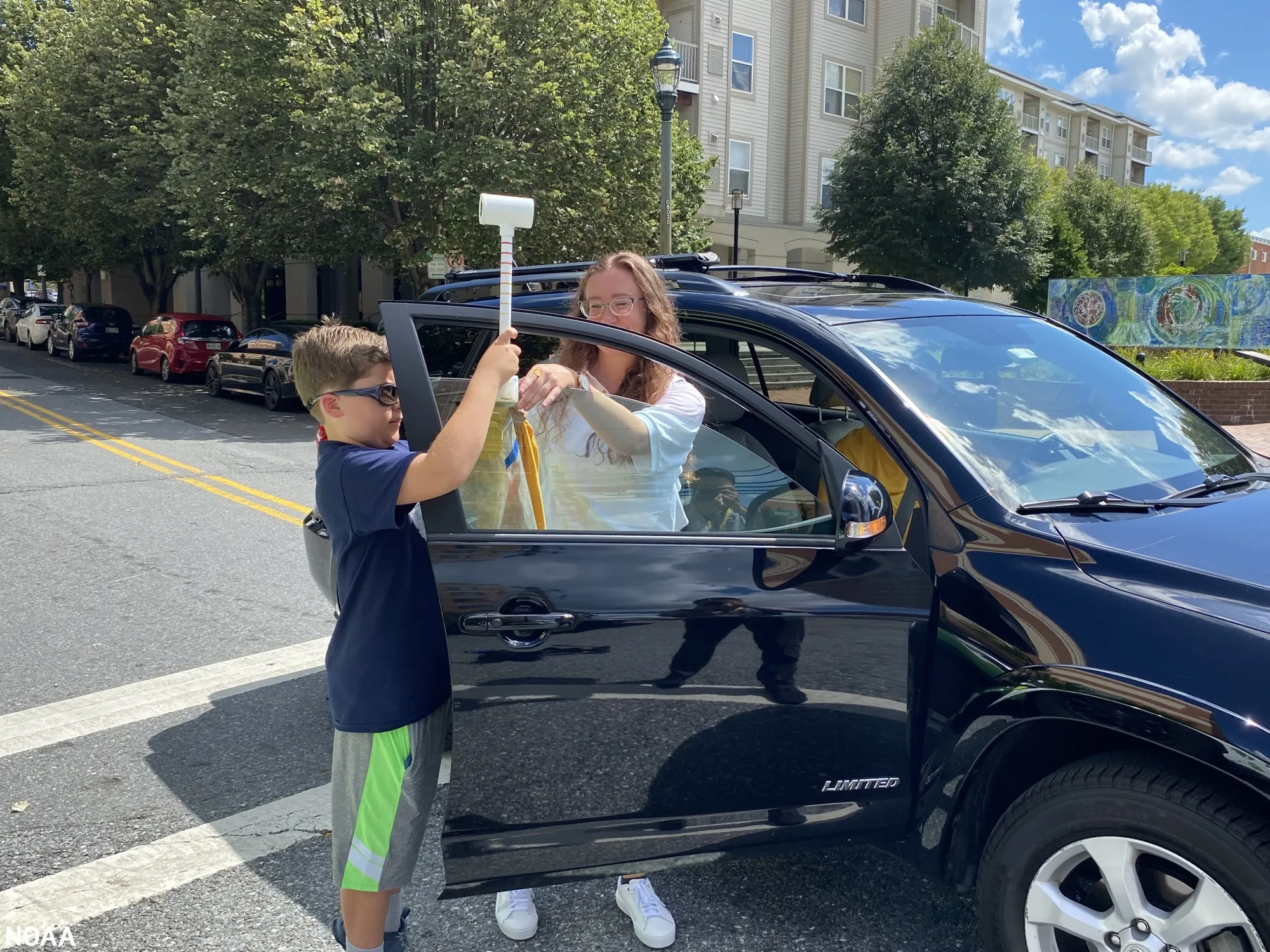 Morgan Zabow, from the National Oceanic and Atmospheric Administration, helps a young volunteer attach a sensor to a car during a heat-mapping campaign&nbsp;in Montgomery County, Maryland.
