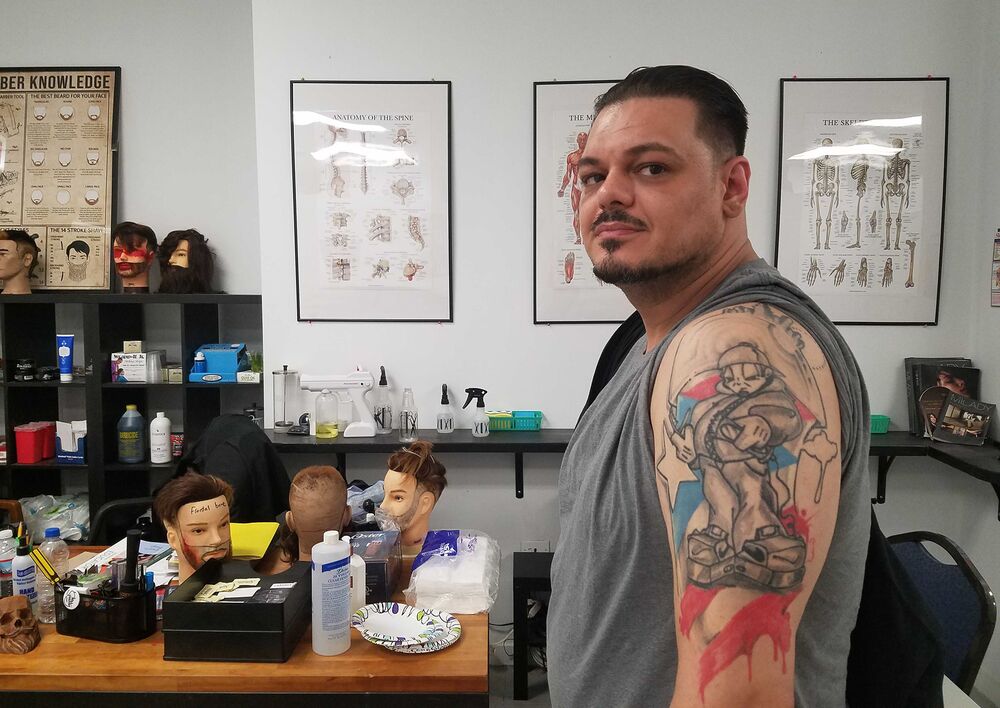 Jimmy Barrett, who is studying to become an instructor, shows off his barber tattoo at Legacy Barber College in Chicago.