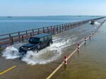 Cars drive&nbsp;along a flooded road on the banks of Poyang Lake after rainfall on June 6.