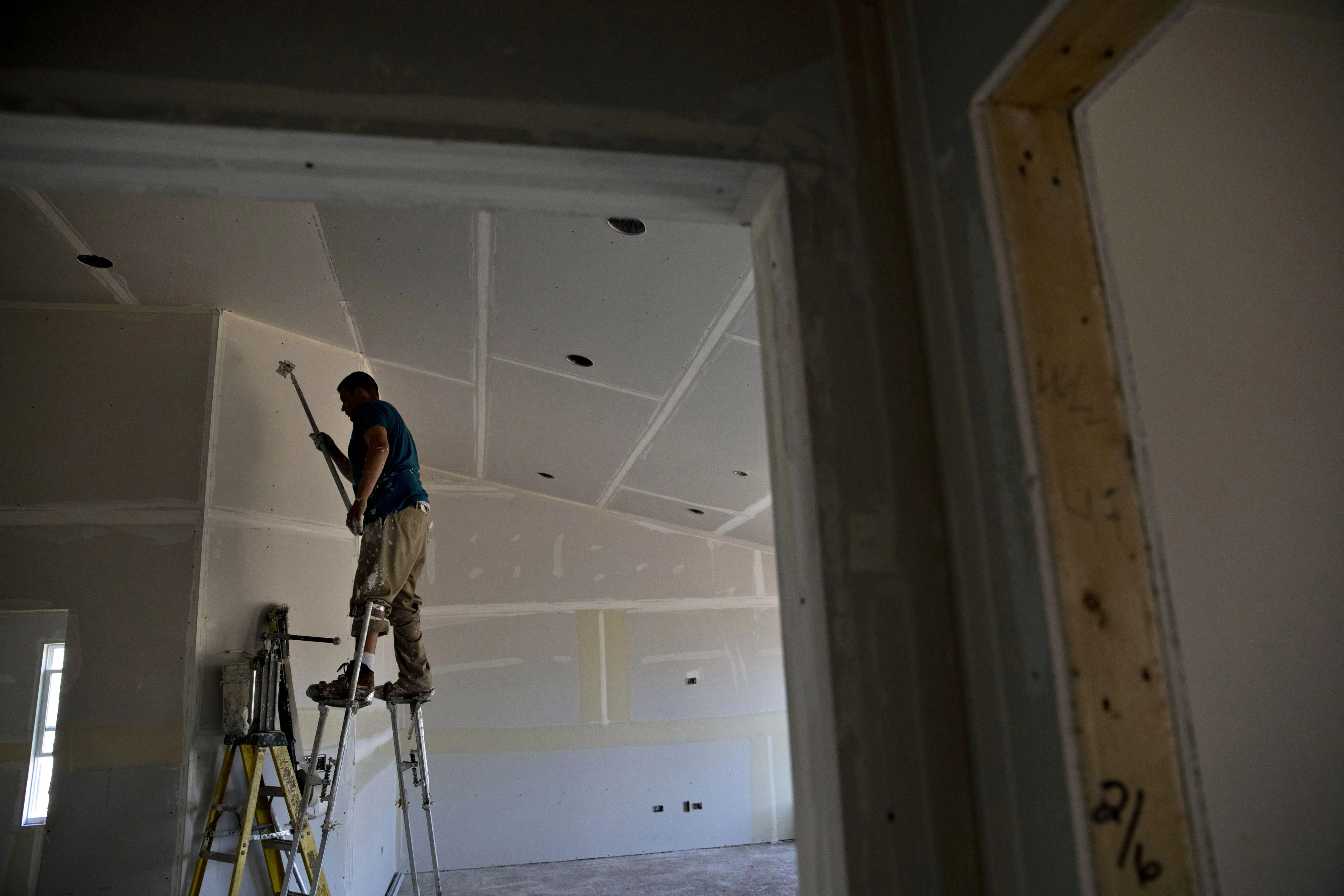 A finisher places tape on drywall seams inside a new home under construction in Plano, Illinois.