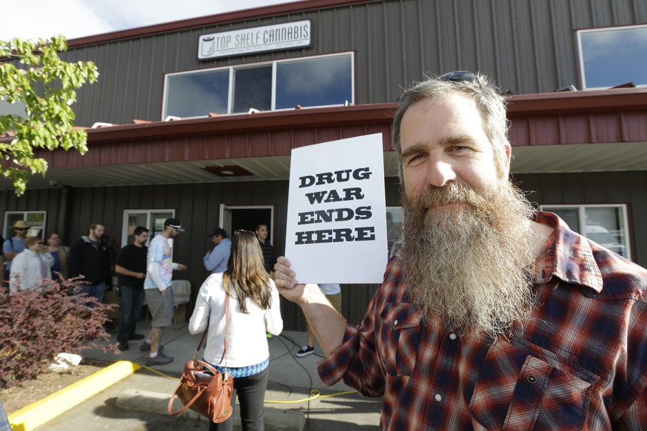 Kevin Nelson, of Bellingham, Washington, holds a sign outside Top Shelf Cannabis. He feels the legalization of marijuana will lead to less crowded jails and be less of a burden on the court system. 
