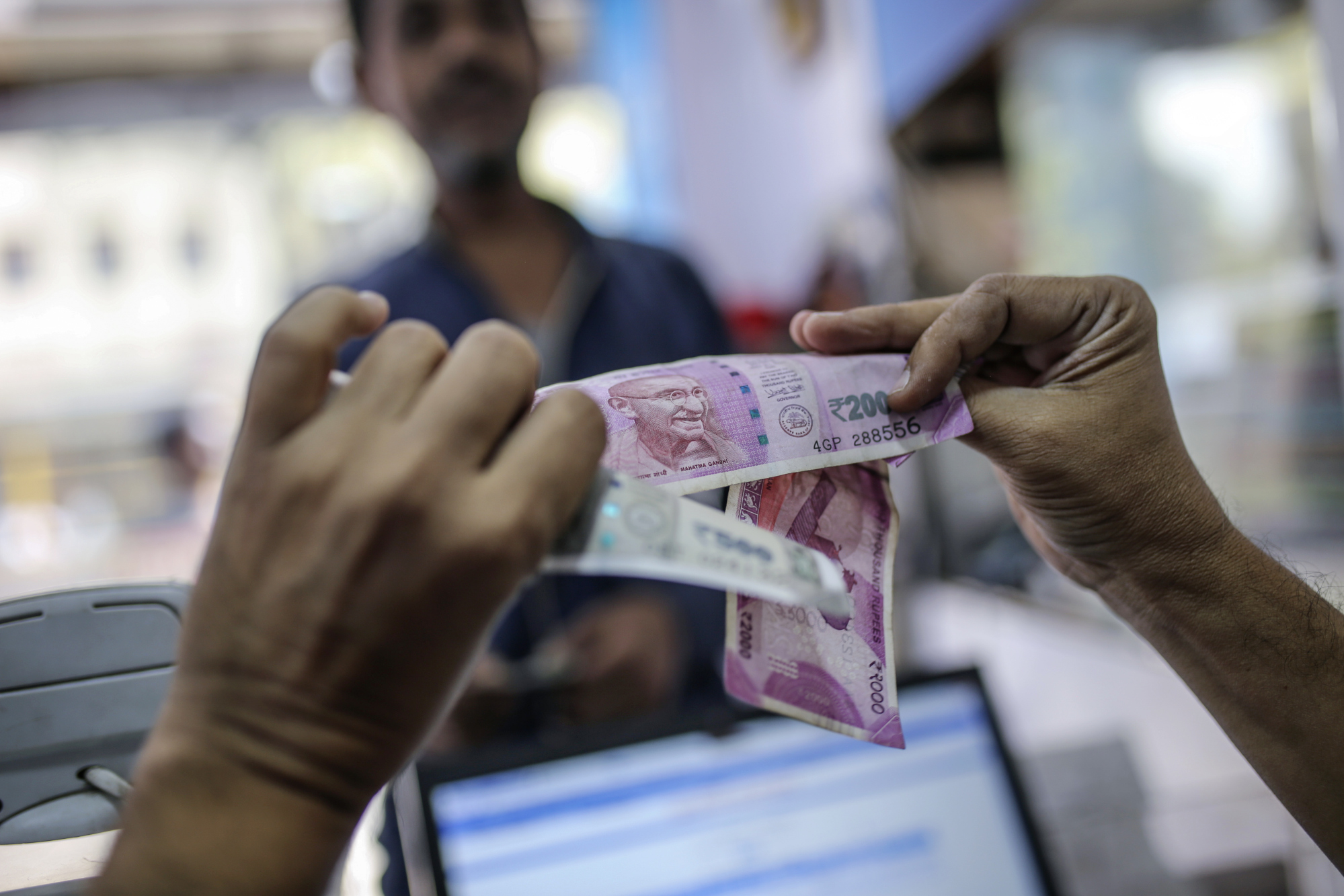 A cashier examines Indian rupee banknotes in Mumbai.