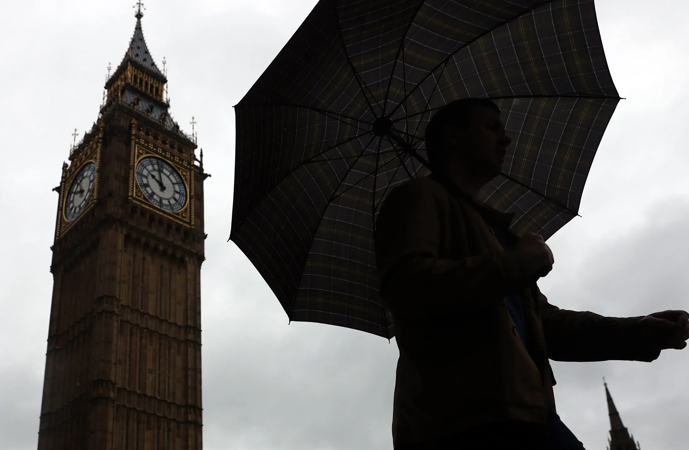 A man shelters under an umbrella as he walks past Big Ben in London, on May 31, 2016.
