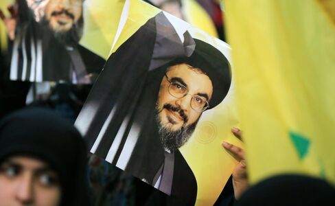A supporter holds a poster showing Hassan Nasrallah as he addresses supporters in Beirut's southern town of Mujammaa Sayyed al-Shuhada, on Jan. 30, 2014.