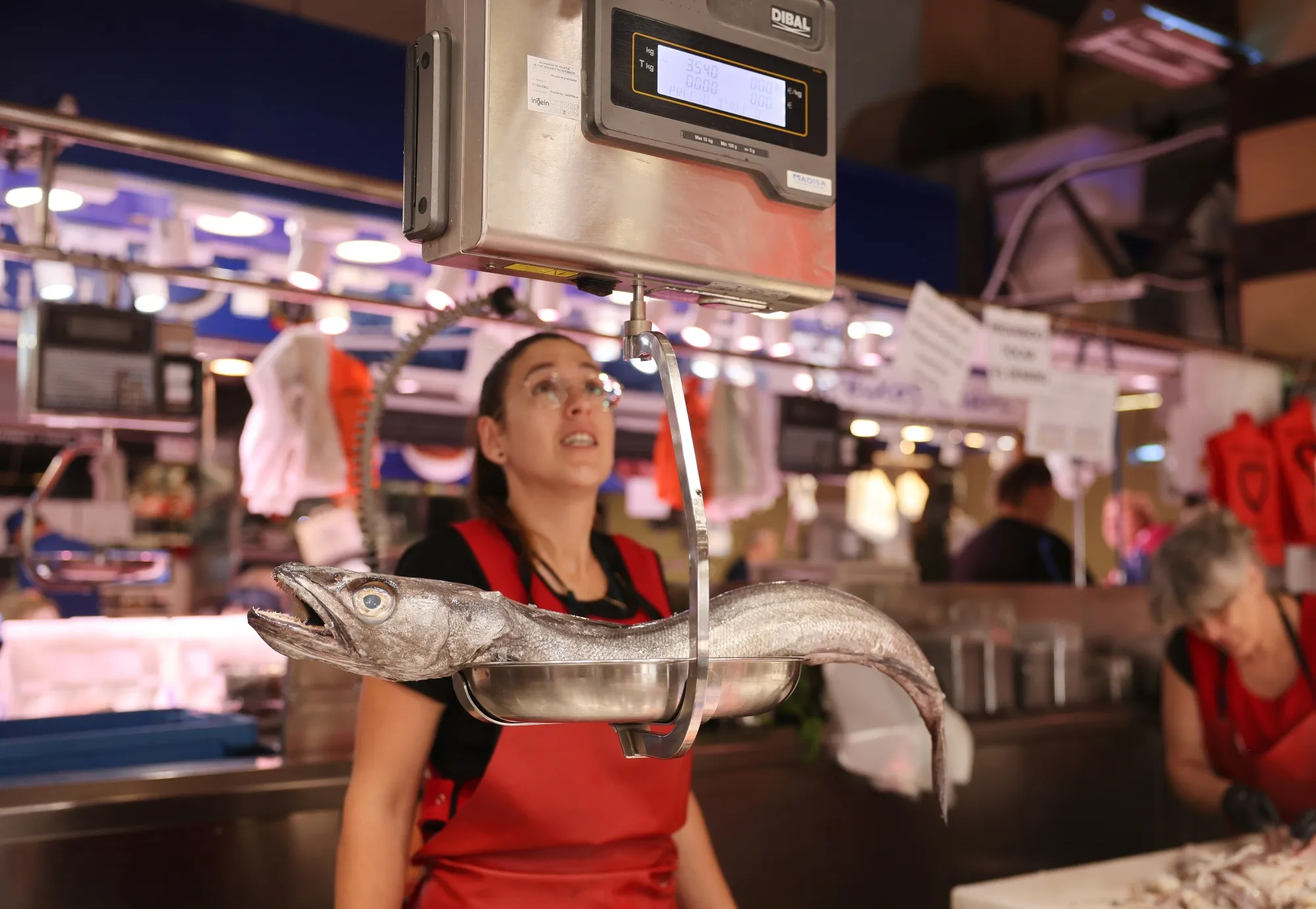 An employee weighs a fresh fish on scales at the Mercat de L'Olivar food market in Palma de Mallorca, Spain, on July 18, 2024.&nbsp;