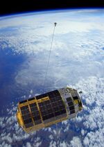 An illustration of a tether extending from the Kounotori transfer vehicle, foreground, shows JAXA’s debris-catching technology. Source: JAXA