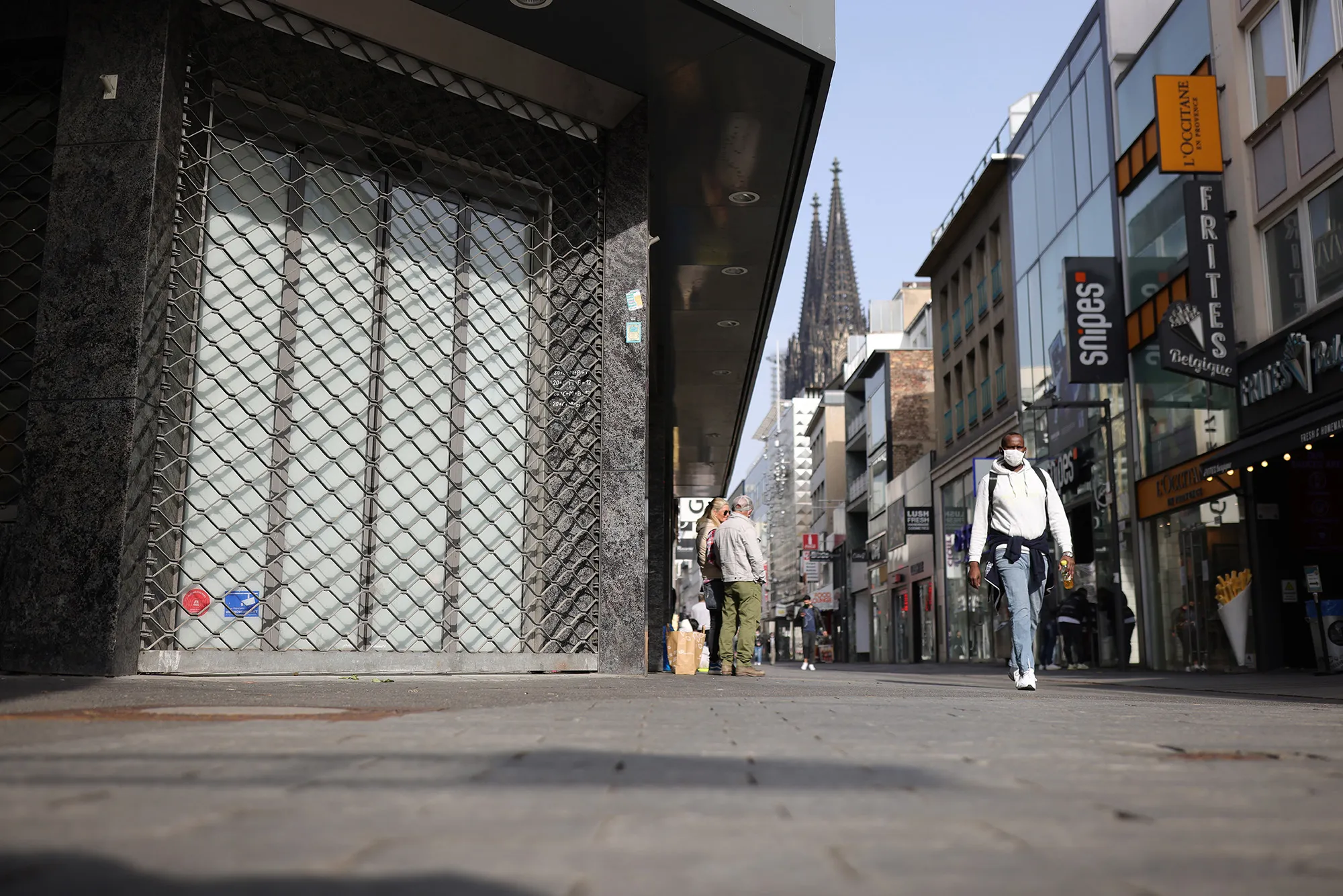 A pedestrian walks past a closed retail shop&nbsp;in Cologne, Germany.