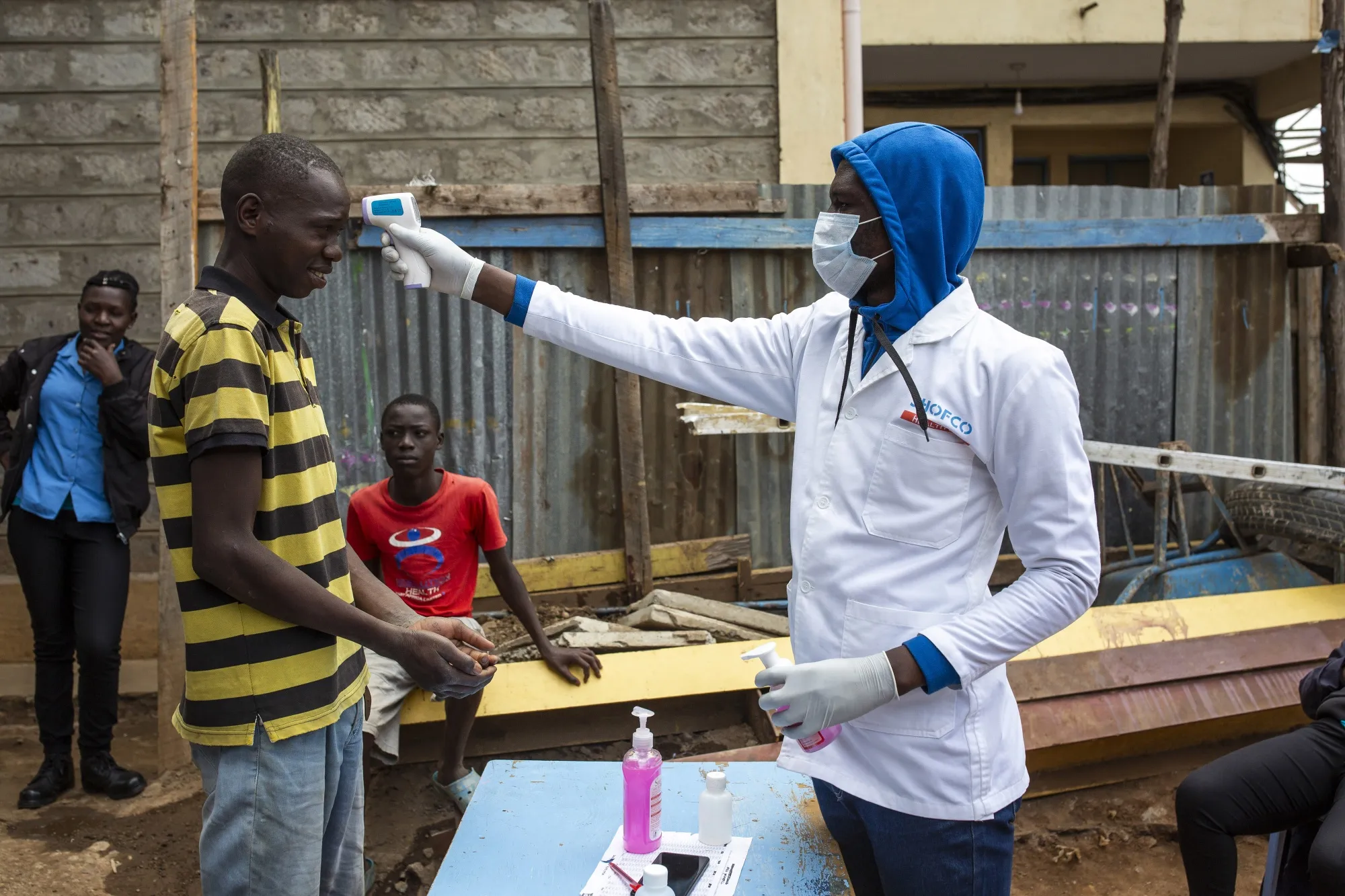 A worker performs a temperature scan on a resident at a temporary hand-washing station in Nairobi, Kenya.