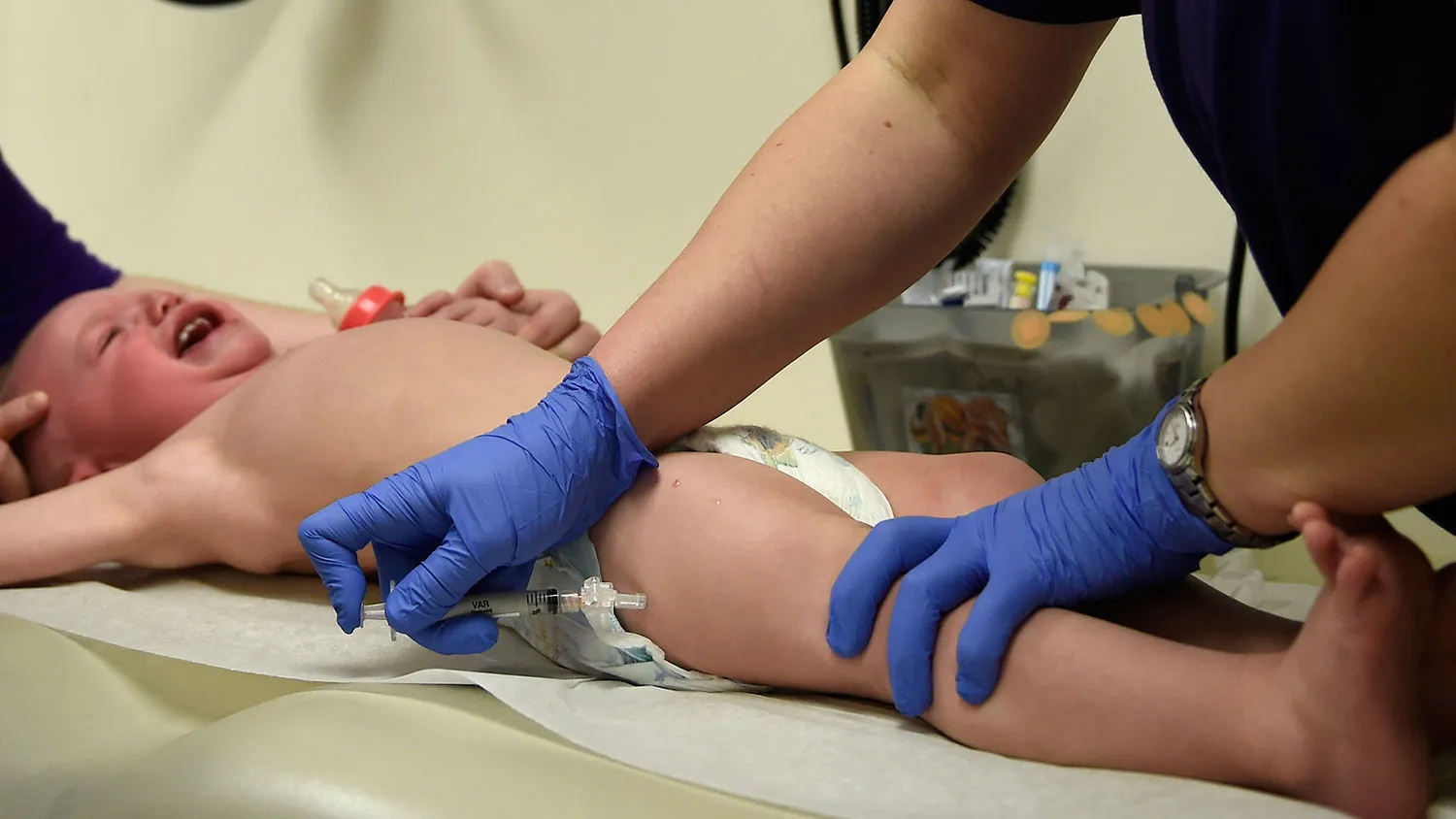 Ashley Walborn of Aurora holds her 1 year old son Nathanyel Jr. as he gets his VAR shot, the last of 6 shots from LPN Jessica Capetillo during his pediatric vaccination at Kaiser Permanente East Medical offices in Denver.
