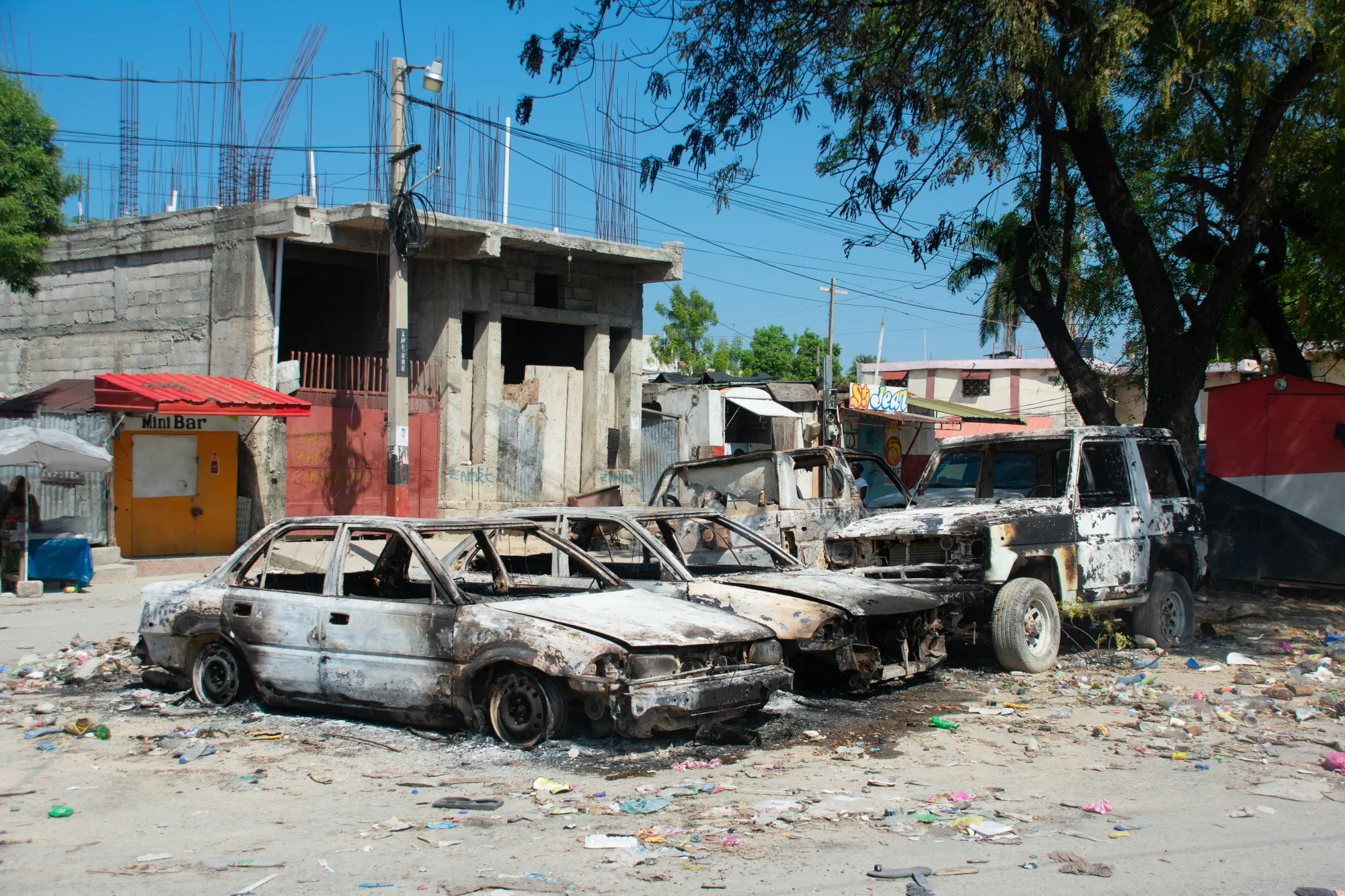 Charred vehicles remain parked as gang violence escalates in Port-au-Prince.
