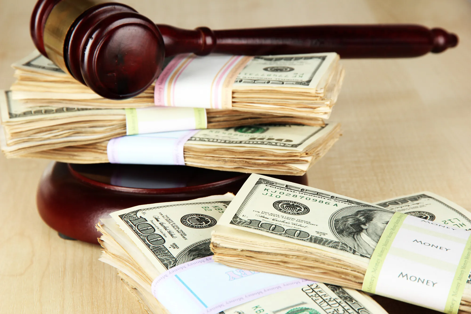 Stacks of money and judges gavel on wooden table