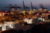 Containers sit stacked beneath gantry cranes in Incheon, South Korea.