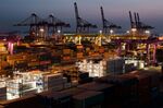 Containers sit stacked beneath gantry cranes in Incheon, South Korea.