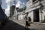 A pedestrian walks through an alleyway as cranes stand in the background in an area slated for redevelopment in Shanghai.