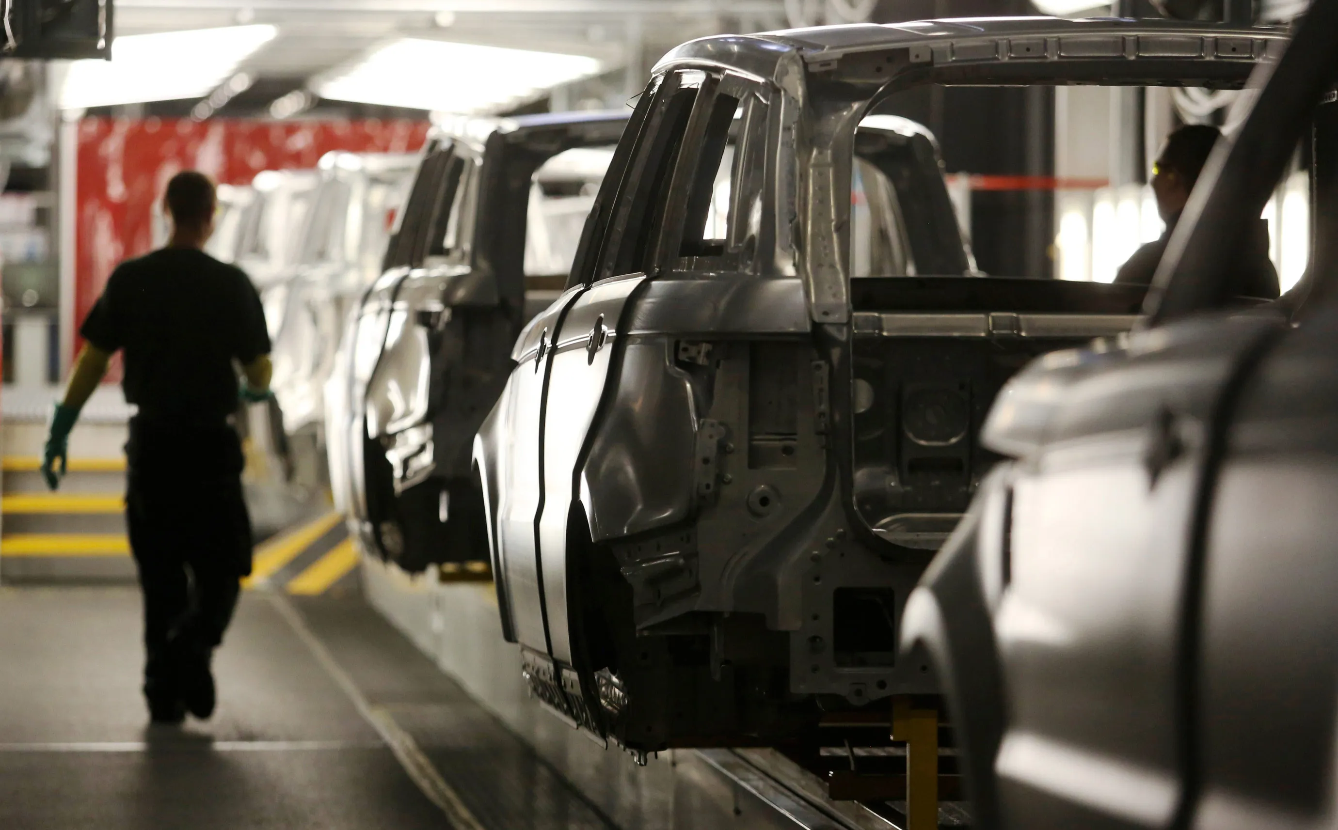 An employee passes the bodywork of Range Rover Sport SUV at Tata Motors Ltd.'s Jaguar Land Rover vehicle manufacturing plant in Solihull.
