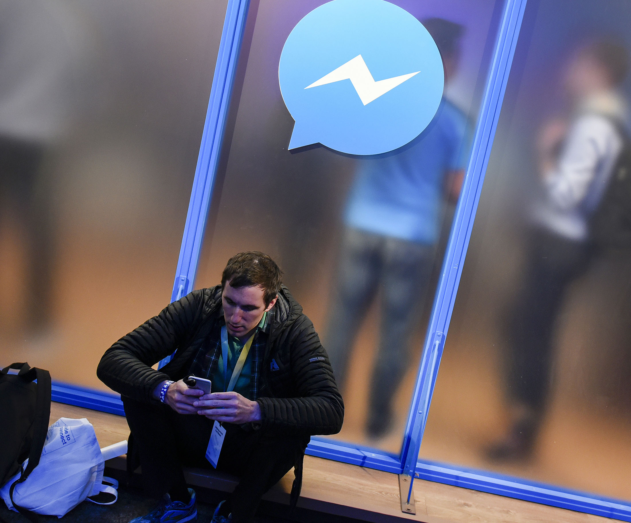 An attendee sits in front of a messenger logo during the Facebook F8 Developers Conference in San Francisco, California.
