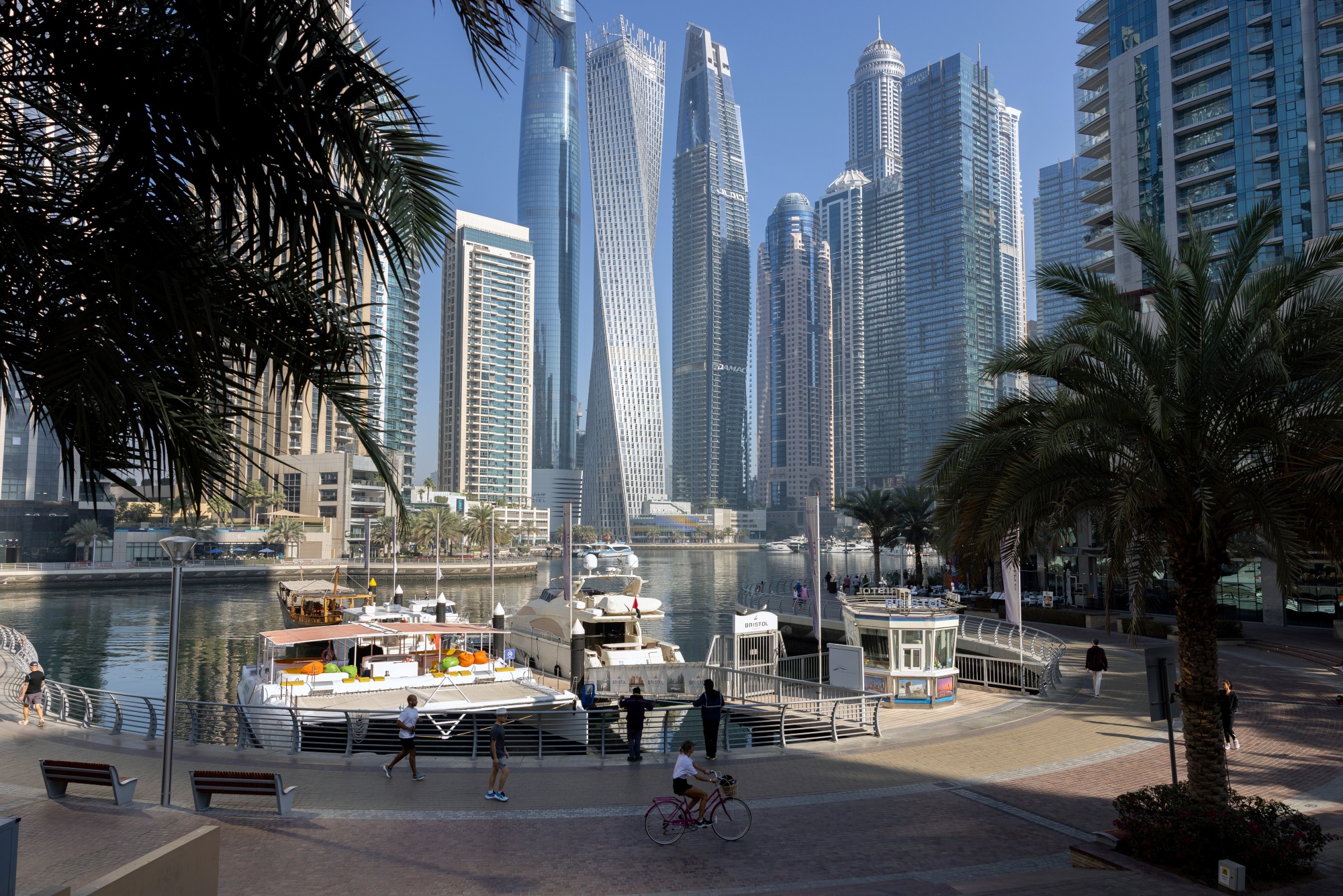 Pedestrians pass boats docked in a harbor in Dubai, United Arab Emirates, on Friday, Feb. 20, 2026. Dubai developers see the luxury property boom continuing in 2026. Photographer: Walaa Alshaer/Bloomberg