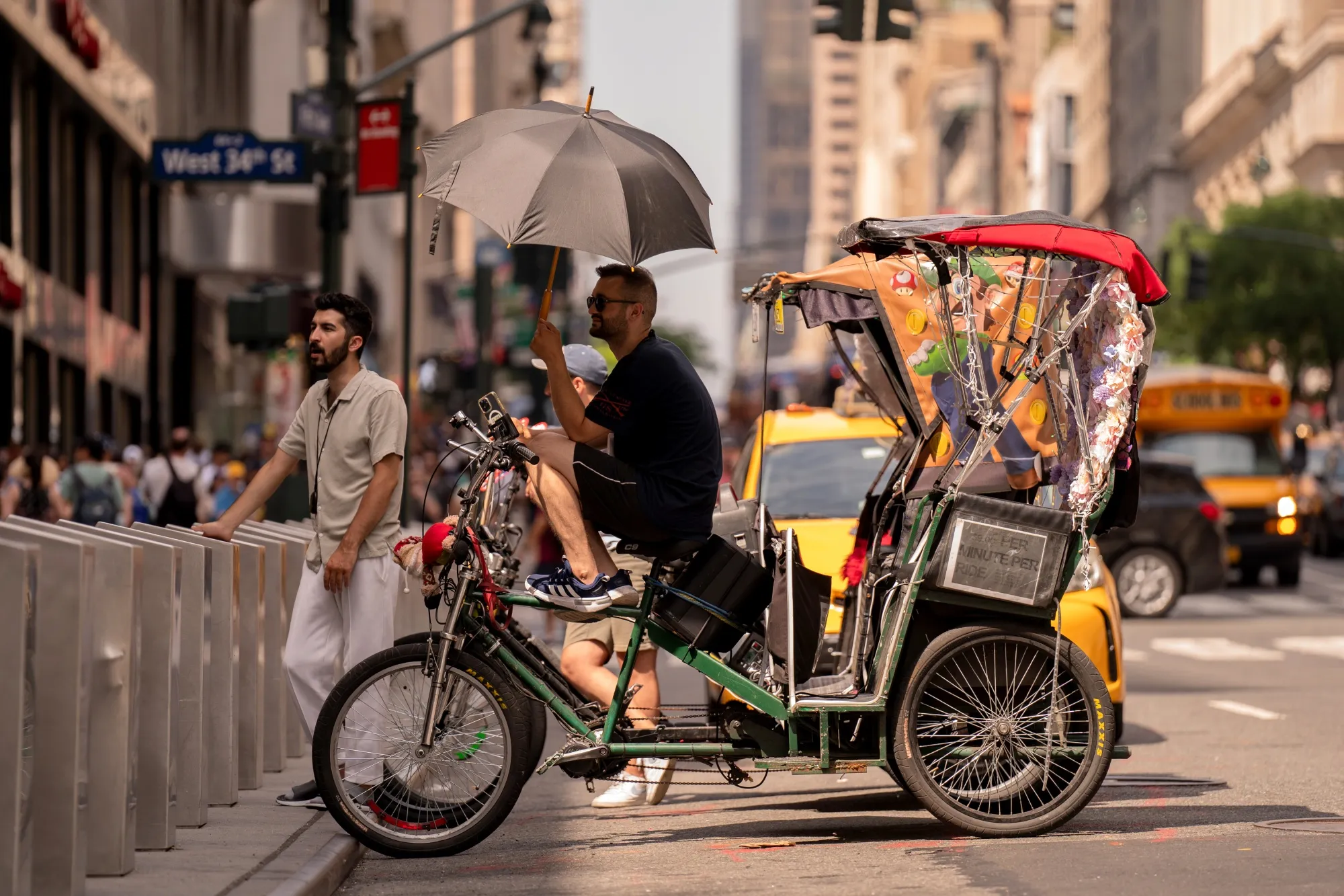 A pedicab driver holds an umbrella during high temperatures in New York.