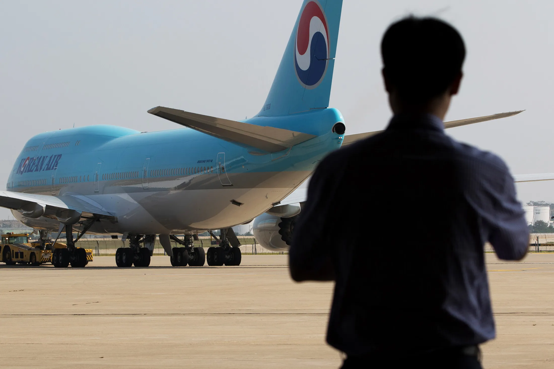 A Korean Air Lines Co. employee looks out as the company's Boeing Co. 747-8 passenger aircraft arrives on the tarmac during a media preview at Incheon International Airport in Incheon, South Korea, on Tuesday, Sept. 1, 2015. Korean Air plans to operate the aircraft from Seoul on the Frankfurt and Singapore routes. The airline also plans to introduce the aircraft on the San Francisco and Hong Kong routes from November.
