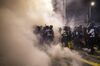 Riot police walk through tear gas as they disperse demonstrators outside the Legislative Council building during a protest in Hong Kong, China, on Tuesday, July 2, 2019. Riot police fired tear gas at protesters who flooded Hong Kong's legislative building Monday evening after smashing their way through entrances in a dramatic escalation of efforts to force the government to withdraw controversial extradition legislation.
