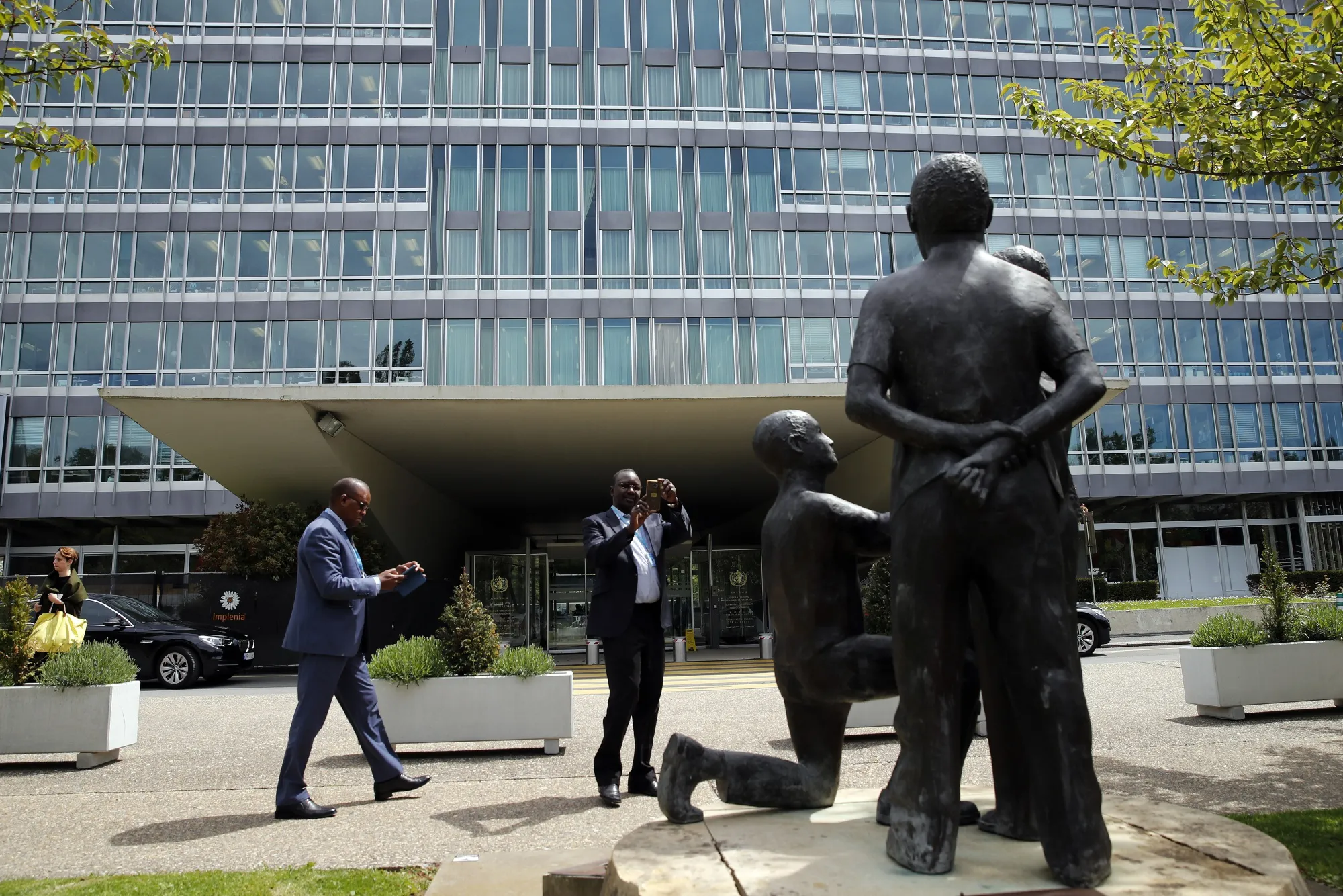 People take photos of a sculpture in front of the World Health Organisation headquarter building in Geneva.