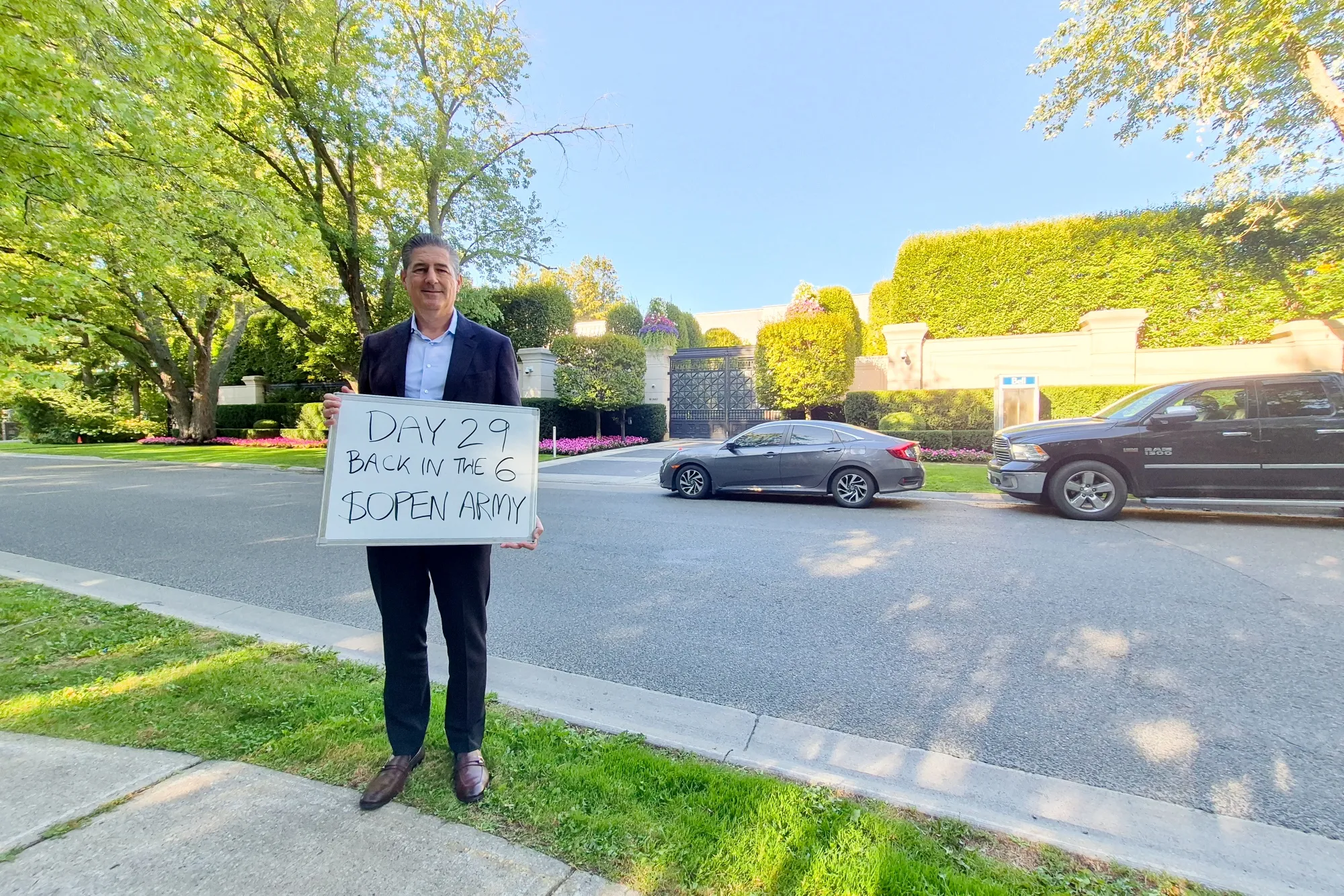 Toronto hedge fund manager Eric Jackson holds a sign outside of rapper Drake’s home.