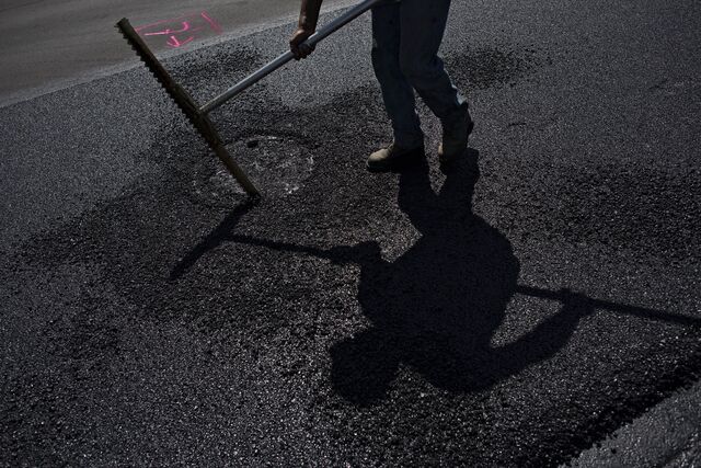 Man repaving road with asphalt