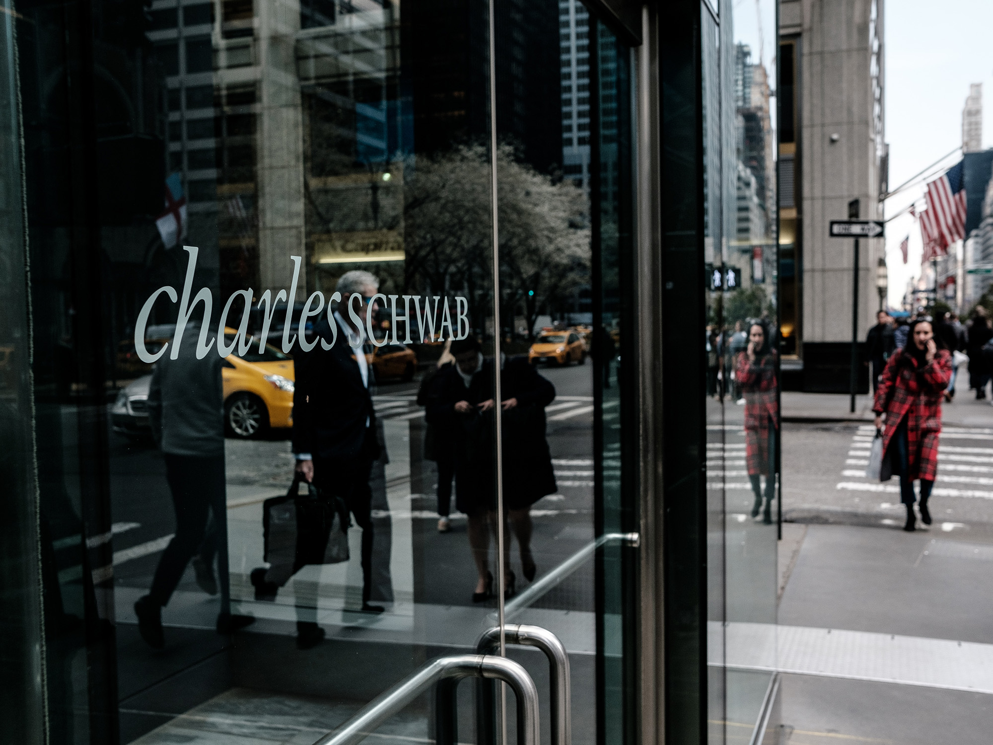 Pedestrians pass in front of a Charles Schwab Corp. office building in New York.