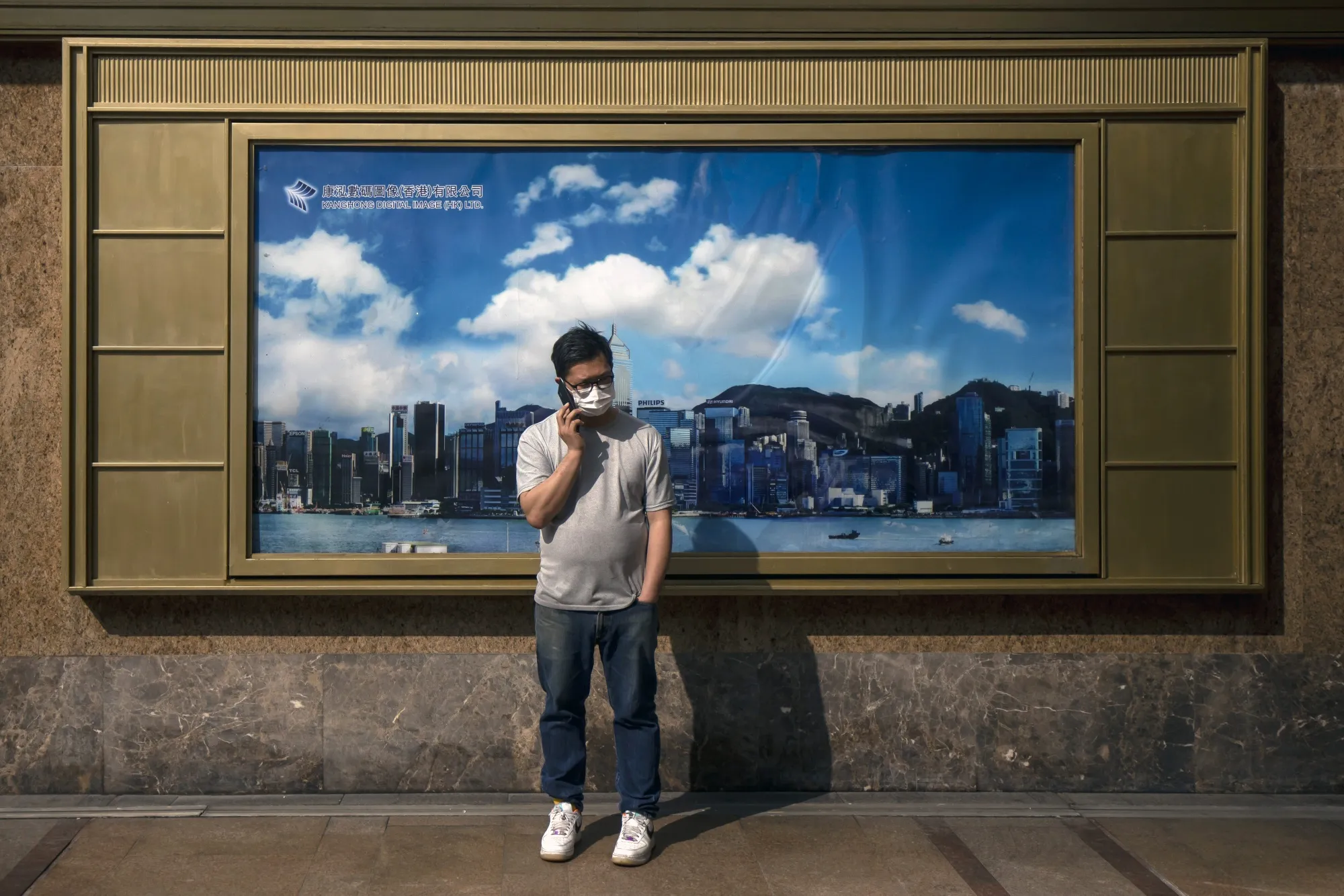 A pedestrian&nbsp;in front of an advertisement featuring the city's skyline in Hong Kong.