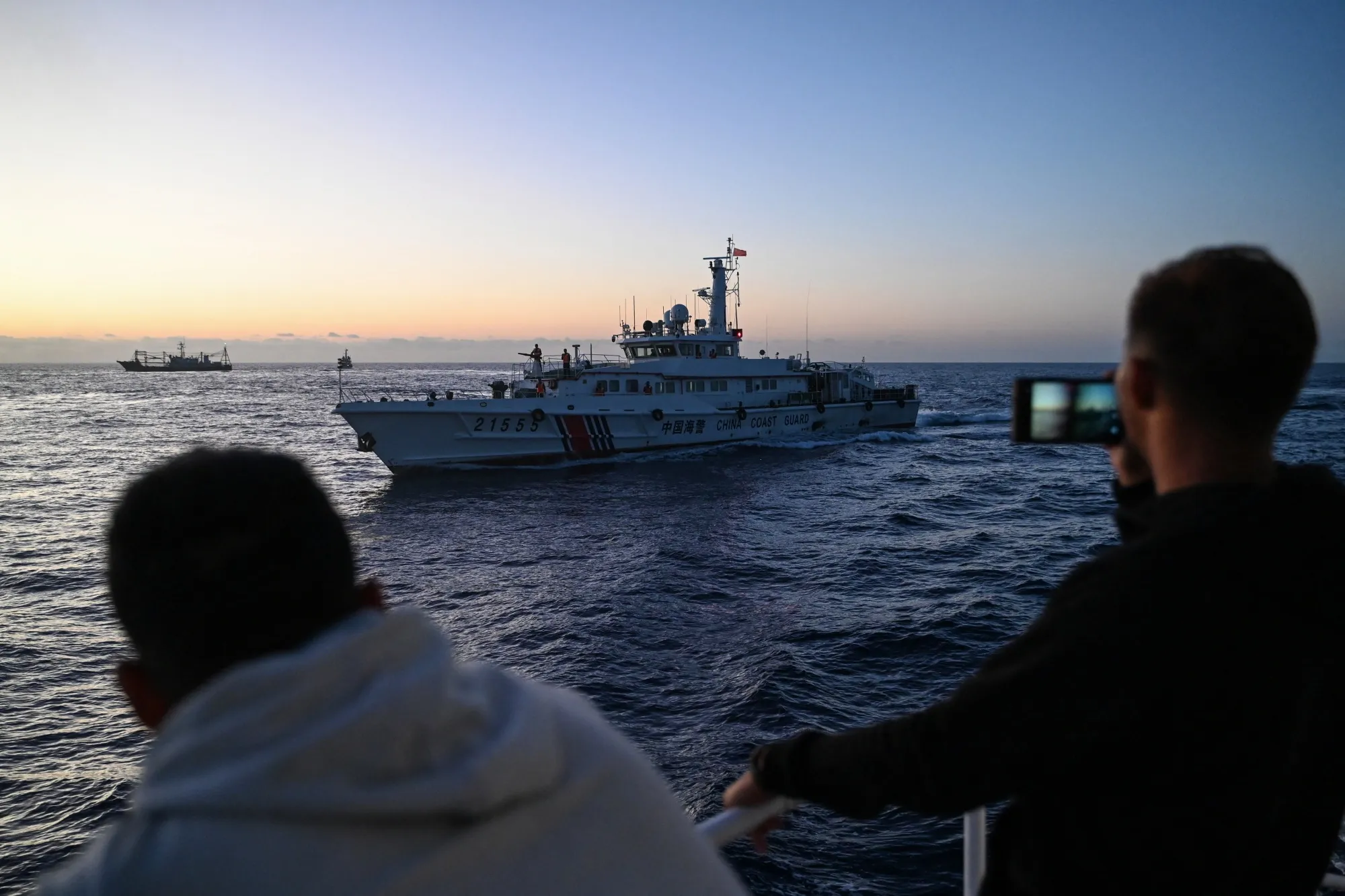 Philippine Coast Guard personnel film&nbsp;a China Coast Guard vessel during a supply mission in the disputed South China Sea on March 5.&nbsp;